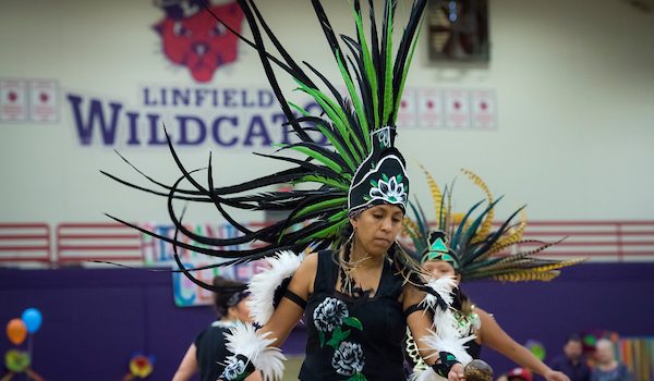 An Aztec dancer wears an elaborate green headdress at Celebración