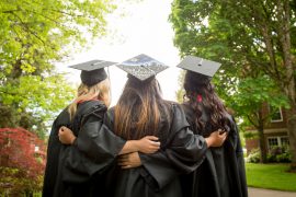 Students stand with camera in caps and gowns