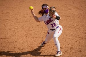 Masked softball player throws a ball