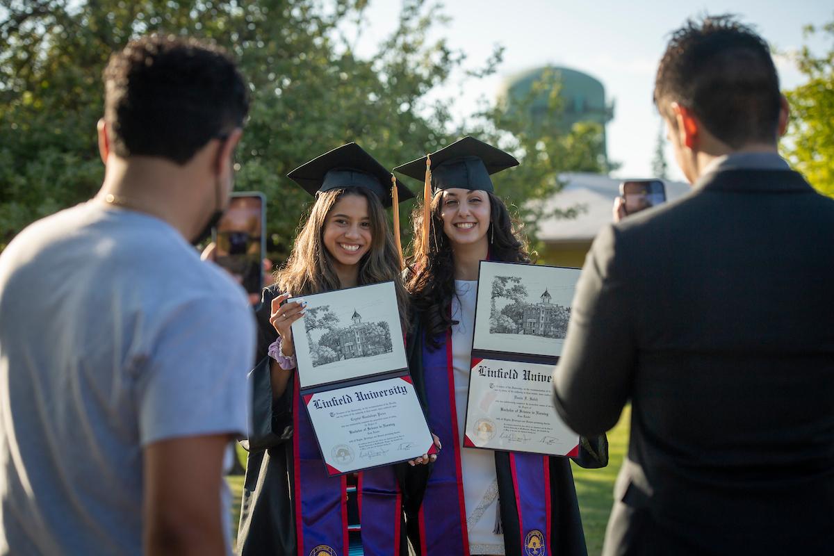 Graduates hold diplomas up to family