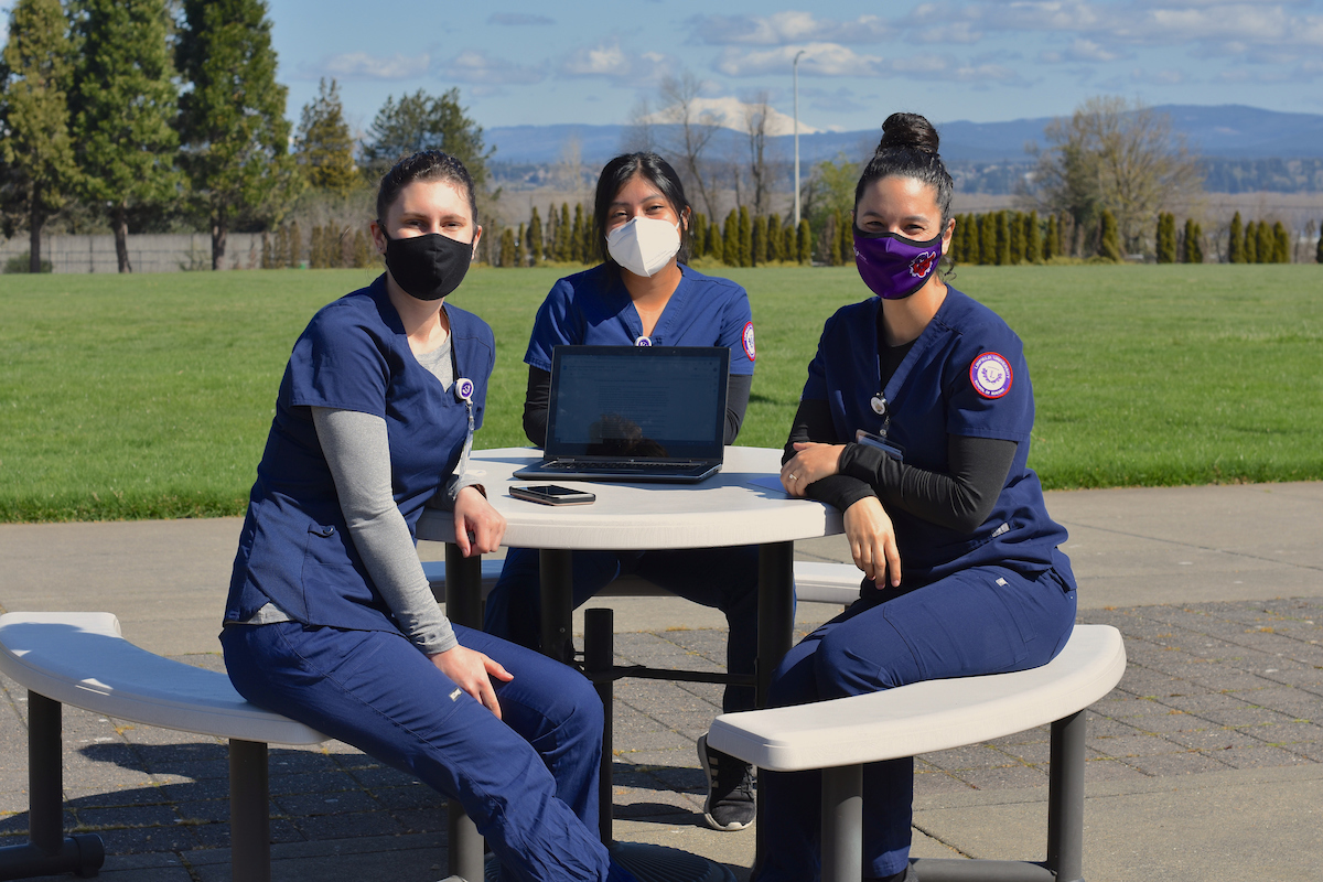 three nursing students study outdoors