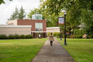 student walks toward theatre building at Linfield