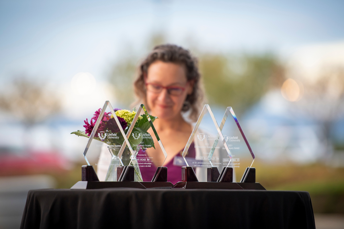 Alumni awards on a table top with person in the background