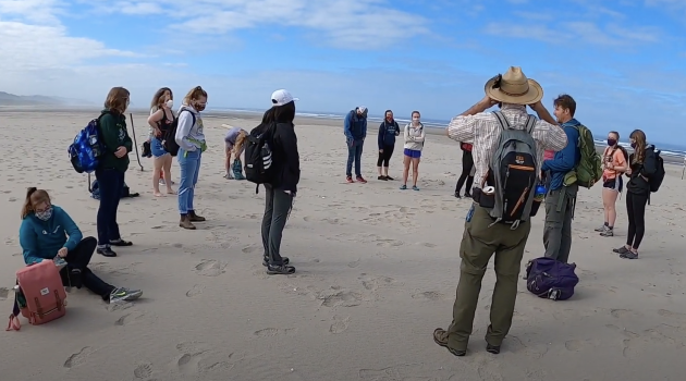 students gather with professor on beach