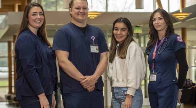 Linfield School of Nursing students Ellie Rogge, Collin Hoyt, Monica Salazar and Sarah Miller are pictured; most are wearing their scrubs.