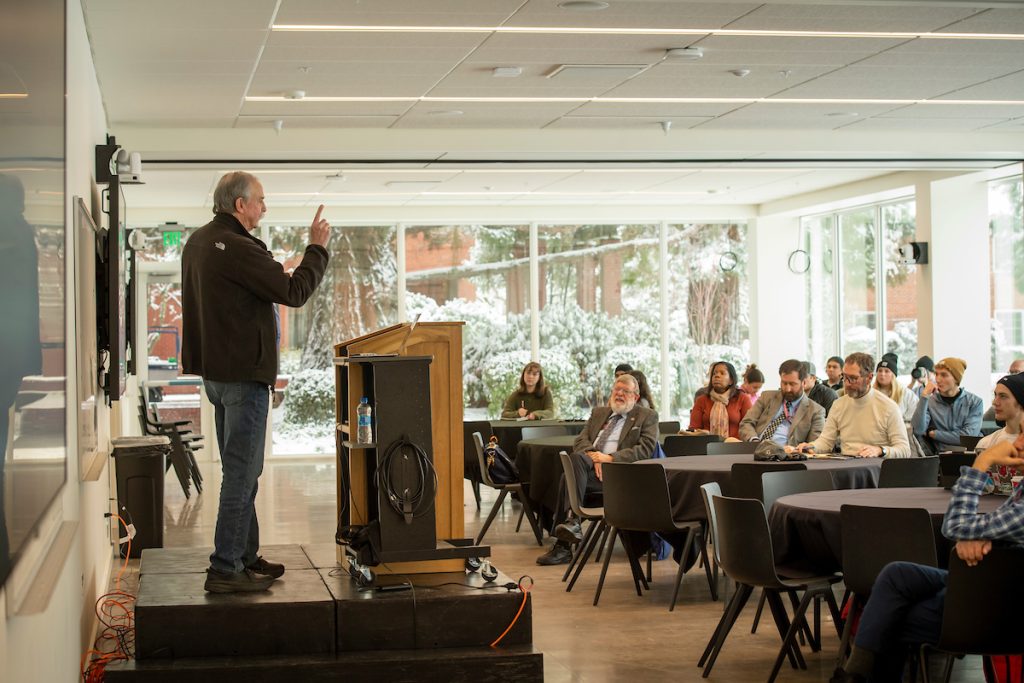 David Wineland addresses a lecture hall full of students.