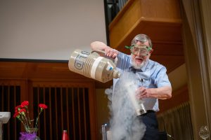 Physicist Bill Phillips pours steaming liquid nitrogen into a vase.