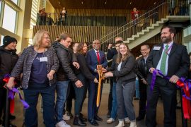 Linfield students, faculty and President Davis moments after cutting a purple ribbon with giant wood scissors.