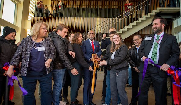 Linfield students, faculty and President Davis moments after cutting a purple ribbon with giant wood scissors.