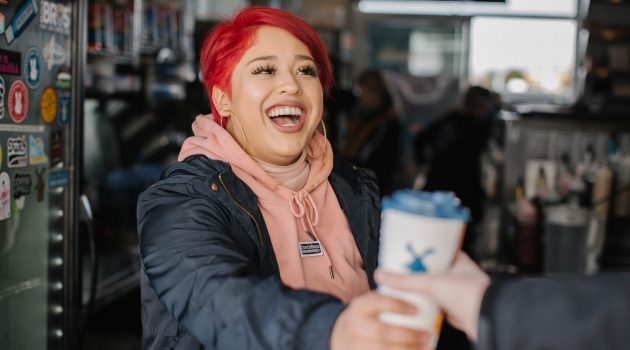 A Dutch Bros. "broista" hands a drink to a customer.