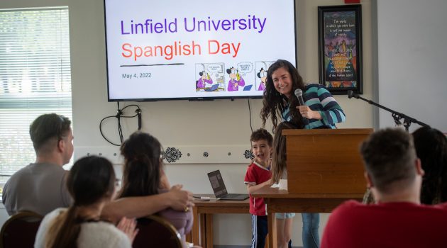A woman and her small son stand in front of a display that says "Linfield University Spanglish Day."