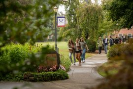 Students walk under a Linfield University sign on the McMinnville campus
