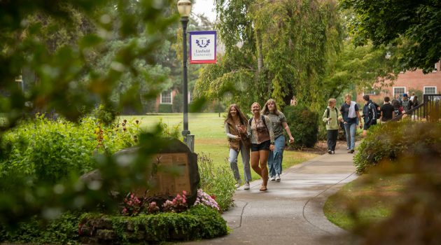 Students walk under a Linfield University sign on the McMinnville campus