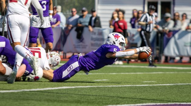 A Linfield football player dives for a ball during the Sept. 30 game against Willamette.