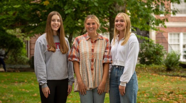 Three Linfield students stand outside an academic hall