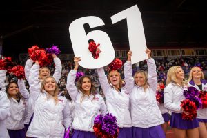 Linfield University cheer team members hold up a big 67 to celebrate securing Linfield’s 67th year of consecutive winning seasons.