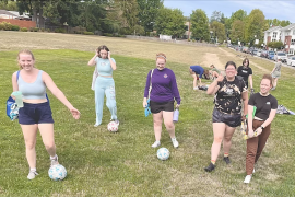 Cast members of "The Wolves" stand in a field practicing soccer.
