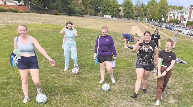 Cast members of "The Wolves" stand in a field practicing soccer.