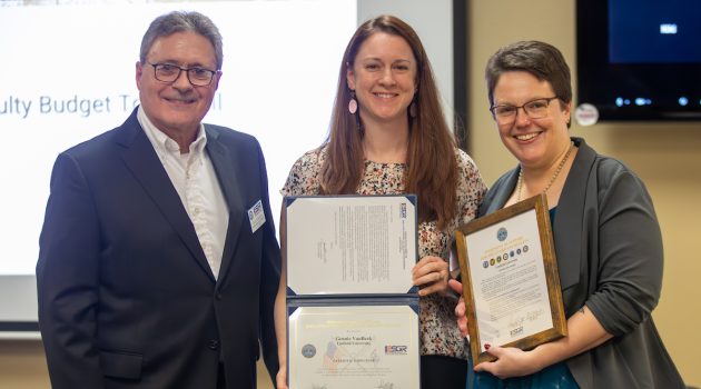 Three people pose with awards together