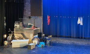 Stage set for "Too Much Light Makes the Baby Go Blind," featuring random piles of objects