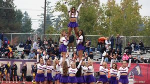 Cheerleaders do a pyramid at a home football game.
