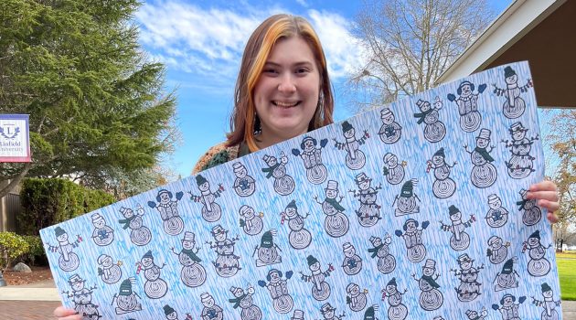 Annemarie Mullet poses with her award-winning wrapping paper, titled "Snowman Friends."