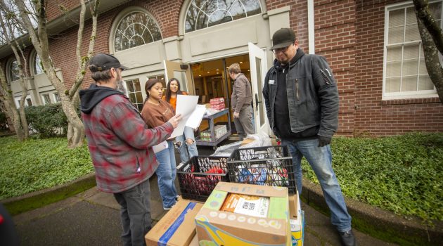 People stand around several crafts of produce and food outside Riley Hall.