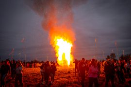 Students stand around an enormous bonfire