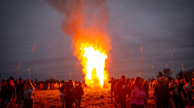 Students stand around an enormous bonfire