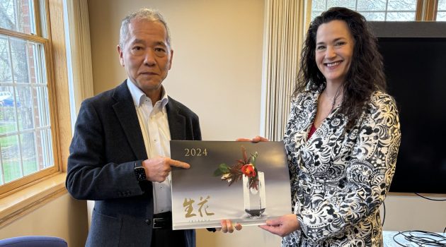 A man in a business suit and woman in a patterned jacket hold a 2024 Japanese calendar