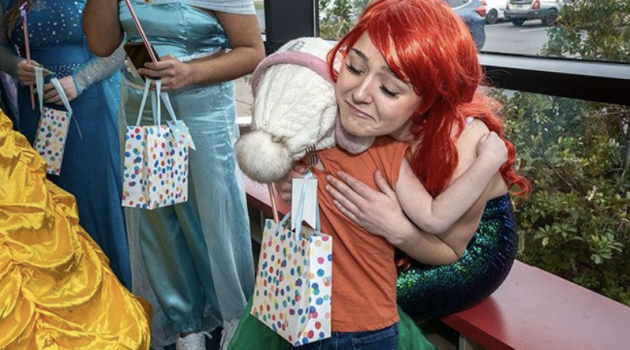 A woman in a mermaid costume hugs a little girl