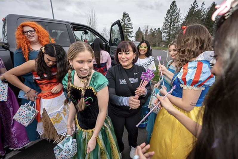 A group of dance team members dressed as Disney Princesses get ready to head into a little girl's brithday party.