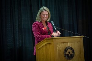 A woman smiles while speaking at a podium