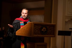 Chaplain Jeremy Richards stands at a podium during Linfield University’s Baccalaureate.