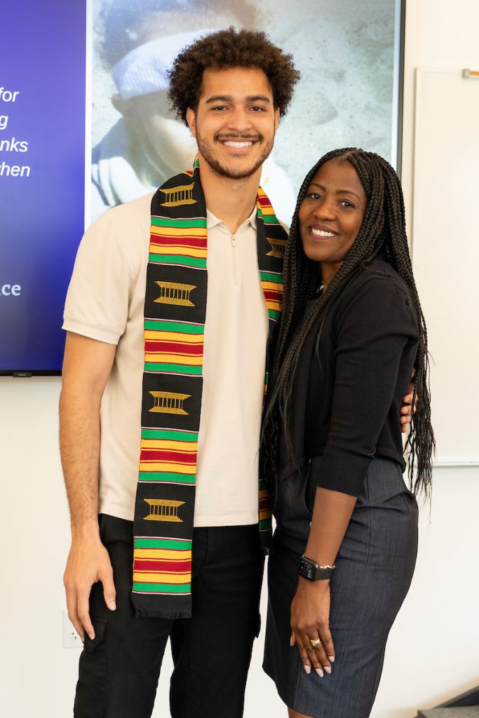A student poses with a family member while wearing a kente-striped stole during the Black Excellence Ceremony at Linfield University.