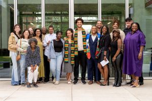 Students wearing a kente-striped stoles pose with family and faculty members during the Black Excellence Ceremony at Linfield University.