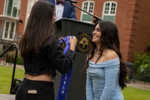 A family member places a purple stole that says Linfield Latina around the neck of a graduate during the Linfield University Latine Dinner.