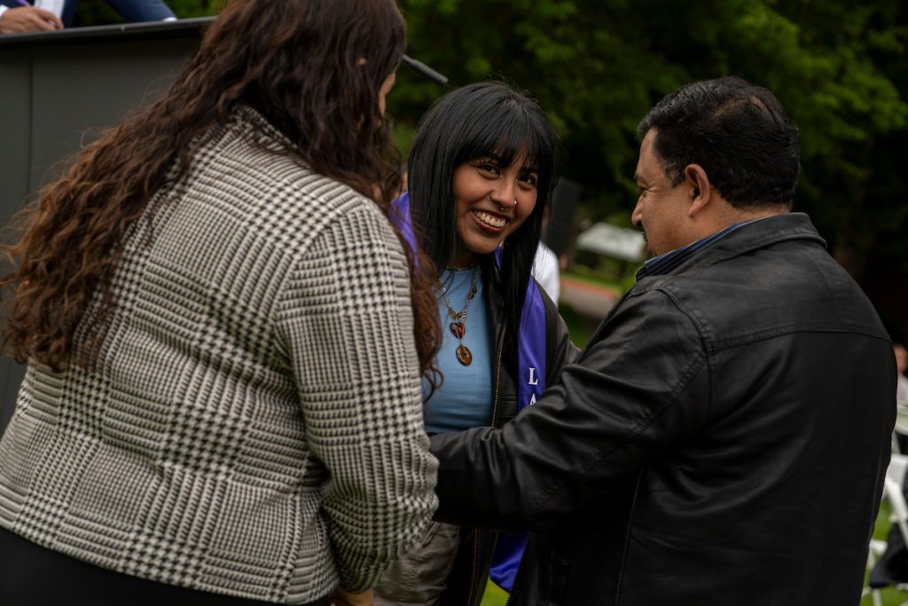 A family member places a purple stole that says Linfield Latina around the neck of a graduate during the Linfield University Latine Dinner.