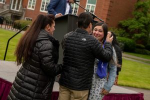 A family member places a purple stole that says Linfield Latina around the neck of a graduate during the Linfield University Latine Dinner.