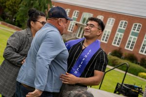 A family member places a purple stole that says Linfield Latino around the neck of a graduate during the Linfield University Latine Dinner.