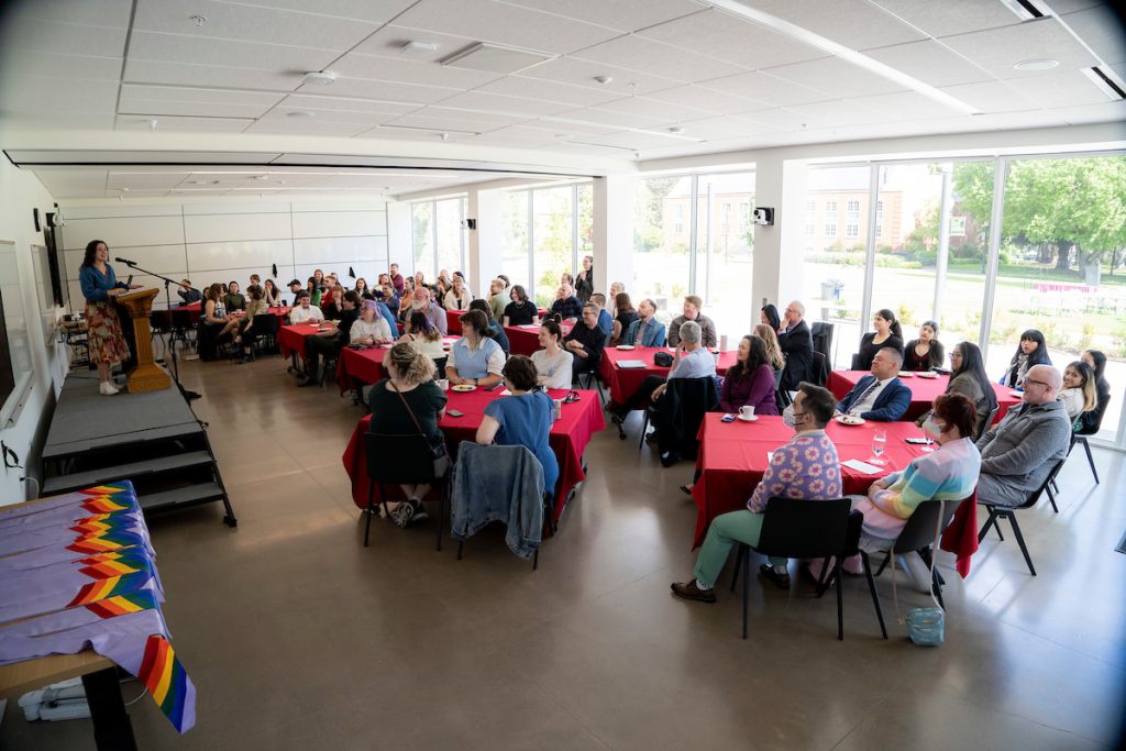 Students, family, staff and faculty watch a speaker during the Linfield University Lavender Celebration; the graduates wear lavender stoles with rainbow trim at the bottom.