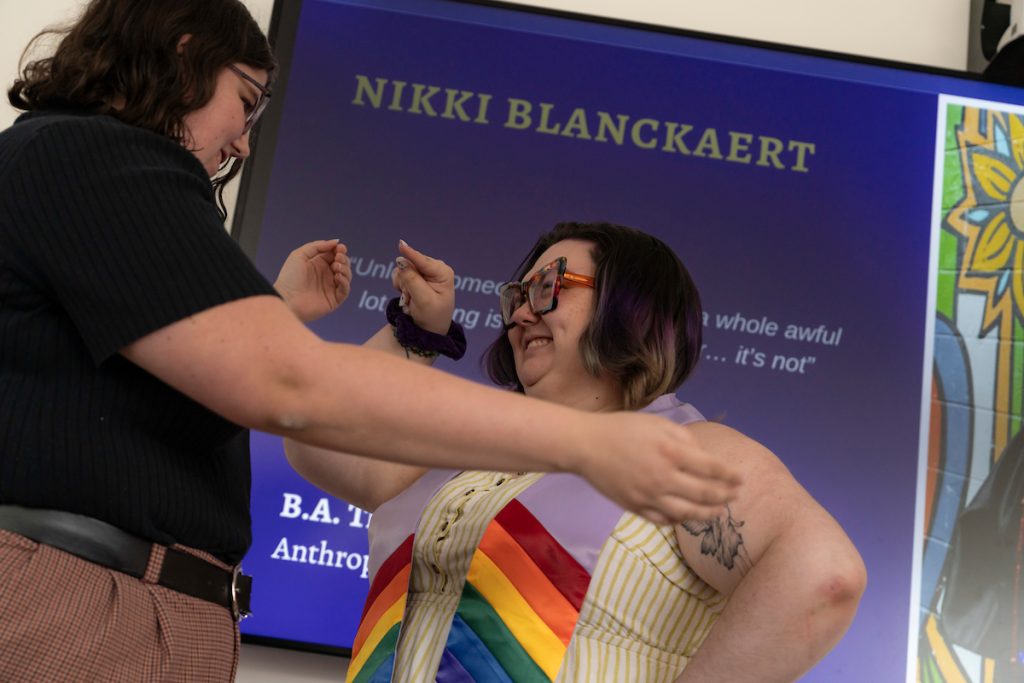 Family members pose next to a graduate during the Linfield University Lavender Celebration; the graduate wears a lavender stole with rainbow trim at the bottom.