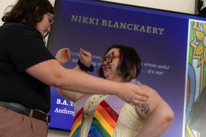 Family members pose next to a graduate during the Linfield University Lavender Celebration; the graduate wears a lavender stole with rainbow trim at the bottom.