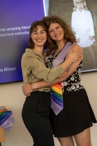 Loved ones pose next to a graduate during the Linfield University Lavender Celebration; the graduate wears a lavender stole with rainbow trim at the bottom.