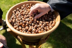 A student places an acorn in a bowl during the 2024 Linfield University Commencement.