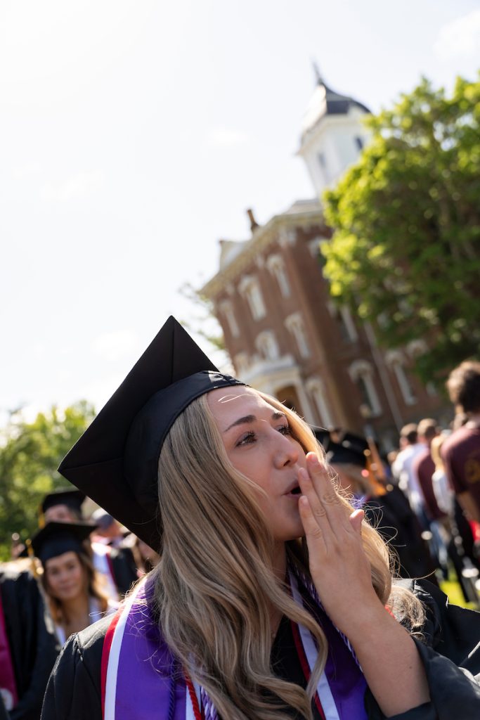 A student dressed in graduation cap and gown smiles during the 2024 Linfield University Commencement.