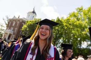 A student in cap and gown smiles at Commencement.