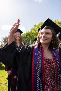 A student dressed in graduation cap and gown smiles during the 2024 Linfield University Commencement.