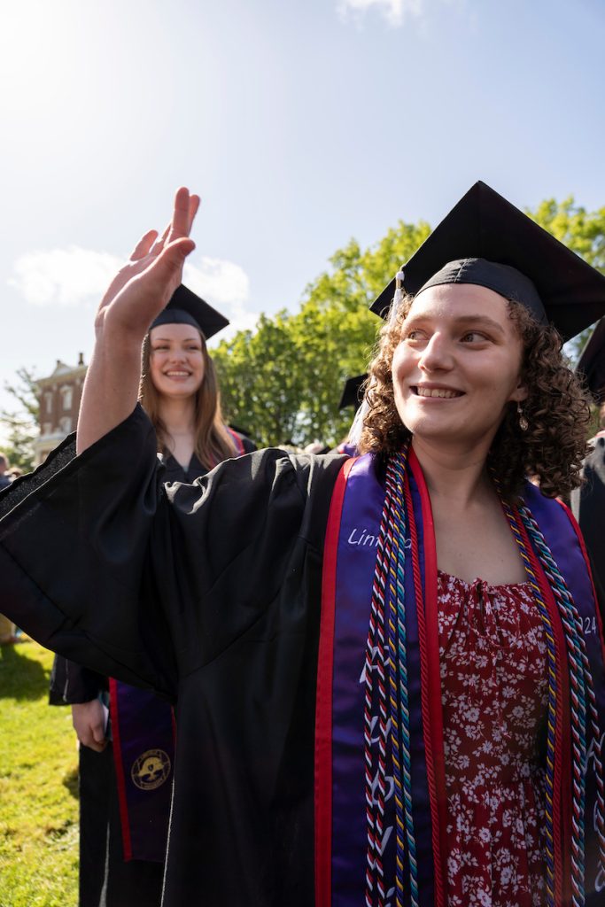 A student dressed in graduation cap and gown smiles during the 2024 Linfield University Commencement.