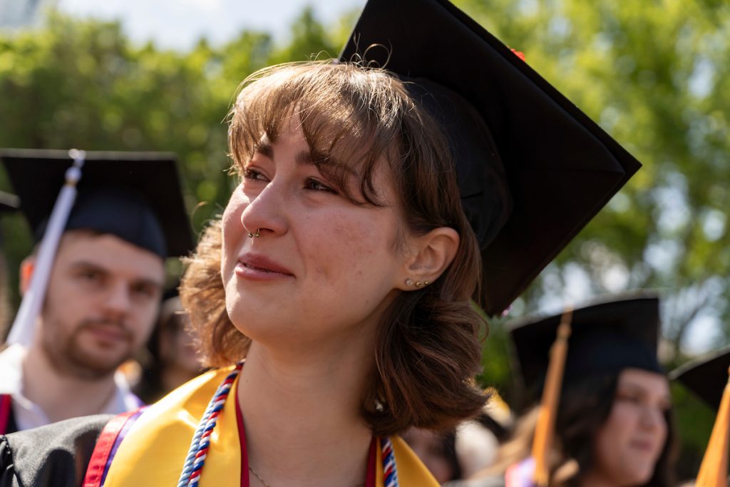 A student dressed in graduation cap and gown smiles during the 2024 Linfield University Commencement.